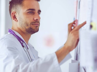 Genç ve kendinden emin erkek doktor portresi tıp ofisinde duruyor.