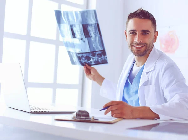 Schöner Arzt spricht mit junger Patientin und macht sich Notizen, während er in seinem Büro sitzt. — Stockfoto