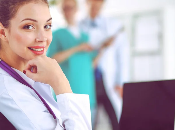 Vakker, ung, smilende kvinnelig lege som sitter ved pulten – stockfoto