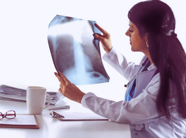 Doctora joven estudiando imagen de rayos X, sentada en el escritorio —  Fotos de Stock