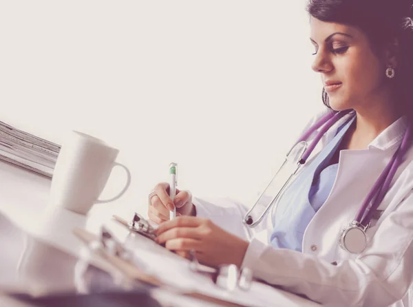 Bonito jovem sorridente médico feminino sentado na mesa — Fotografia de Stock