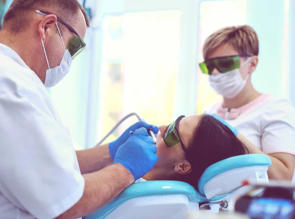 Portrait of a dentist who treats teeth of young woman patient — Stock Photo, Image