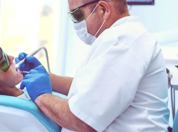 Homem dentista trabalhando em seus pacientes dentes — Fotografia de Stock
