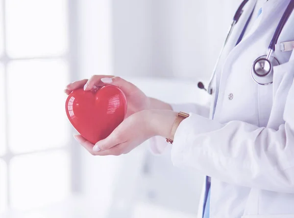 Doctora con estetoscopio sosteniendo el corazón, sobre fondo claro —  Fotos de Stock