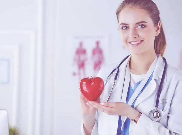 Ärztin mit Stethoskop, das Herz hält, auf hellem Hintergrund — Stockfoto