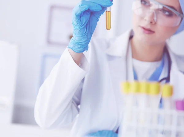 Een vrouwelijke medische of wetenschappelijke onderzoeker of vrouwelijke arts die in een laboratorium naar een reageerbuis met heldere oplossing kijkt — Stockfoto
