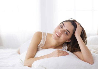 Güzel bir kadın yatağında uzanıyor.