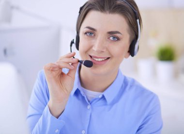 Ofisinde kulaklık takmış, telefon operatörü olarak çalışan ciddi ve güzel bir genç kadın.