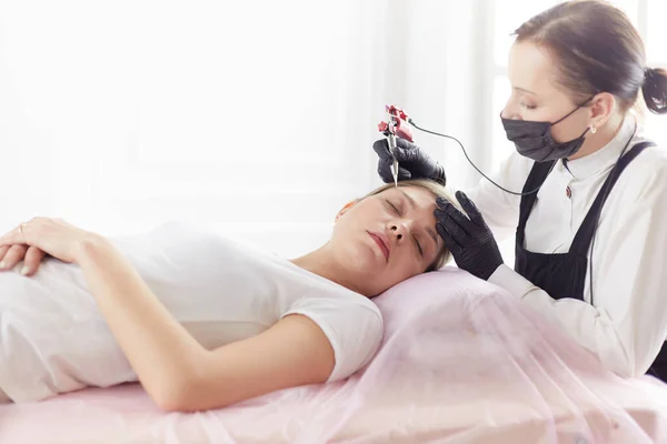 Young woman undergoing procedure of eyebrow permanent makeup in beauty salon — Stock Photo, Image