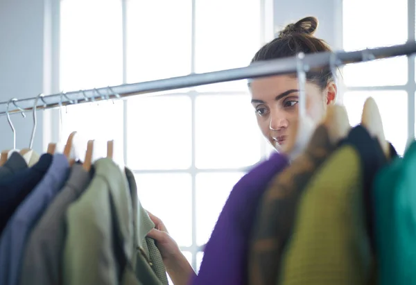 Mooie jonge stylist bij rek met hangers — Stockfoto