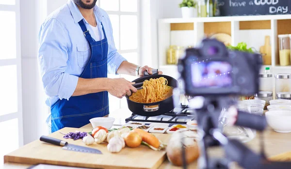 Homem segurando saco de papel cheio de mantimentos no fundo da cozinha. Compras e conceito de comida saudável — Fotografia de Stock