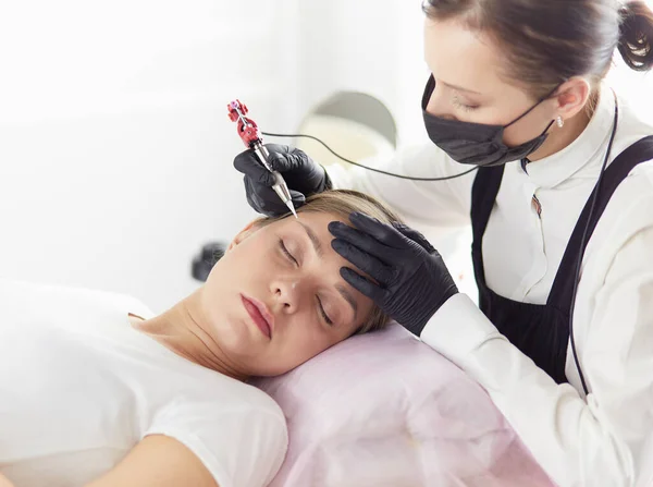 Молодая женщина проходит процедуру постоянного макияжа бровей в салоне красоты — стоковое фото