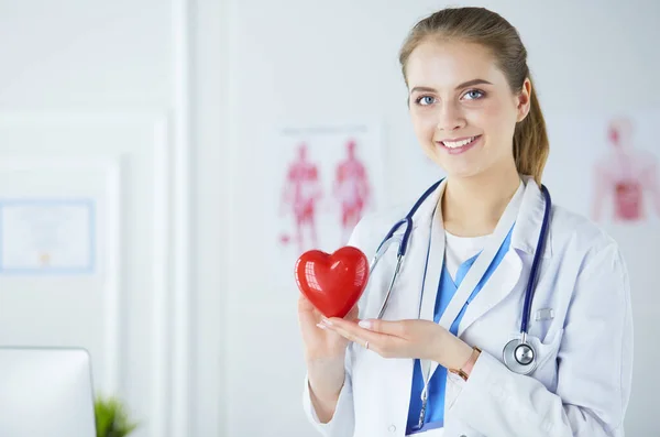 Médecin femme avec stéthoscope tenant le cœur, sur fond clair — Photo