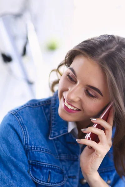 Mladá žena v kavárně pije kávu a mluví do mobilního telefonu — Stock fotografie