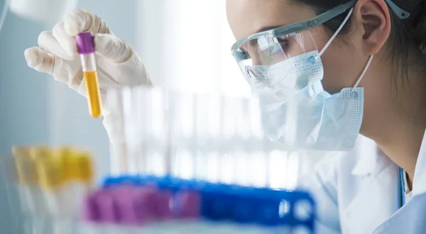 Um pesquisador médico ou científico ou um médico olhando para um tubo de ensaio de solução líquida verde em um laboratório — Fotografia de Stock