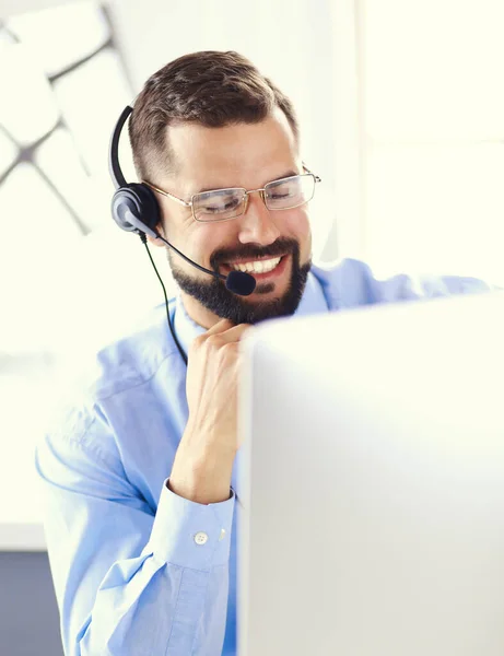 Retrato de un joven con un auricular frente a una computadora portátil — Foto de Stock