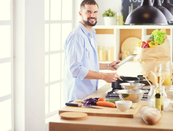 Homme suivant la recette sur tablette numérique et la cuisine savoureuse et saine dans la cuisine à la maison — Photo