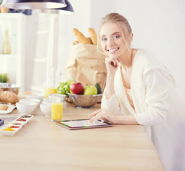 Mooie jonge vrouw met behulp van een digitale tablet in de keuken — Stockfoto