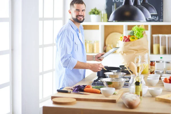 Manusia mengikuti resep pada tablet digital dan memasak makanan lezat dan sehat di dapur di rumah — Stok Foto