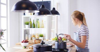 Evdeki mutfakta yemek pişiren güzel genç bir kadın.