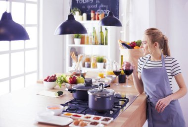 Güzel kadın mutfakta şarap içiyor.