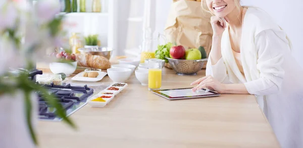 Hermosa joven usando una tableta digital en la cocina — Foto de Stock