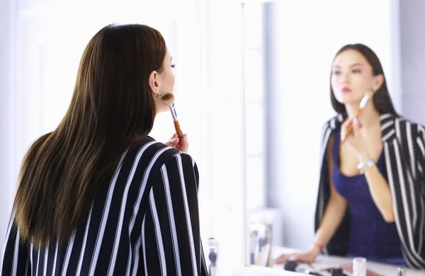 漂亮的女孩照镜子，用大刷擦化妆品 — 图库照片