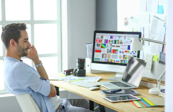 Porträt eines jungen Designers, der im Grafikstudio vor Laptop und Computer sitzt, während er online arbeitet. — Stockfoto