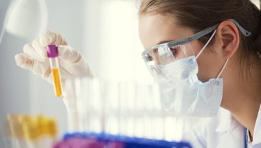 Laboratuvarda sıvı yeşil çözeltiye bakan bir tıbbi veya bilimsel araştırmacı ya da doktor