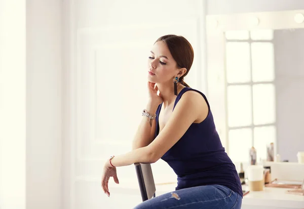 Young woman sitting on a chair isolated over white background — Stock Photo, Image