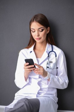 Genç bayan doktor telefonunuzla oturuyor.