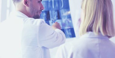 Yakışıklı doktor genç bayan doktorla konuşuyor ve ofisinde otururken notlar alıyor..