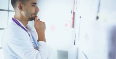 Genç ve kendinden emin erkek doktor portresi tıp ofisinde duruyor.