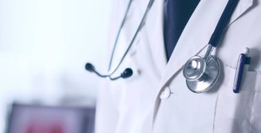 Genç ve kendinden emin erkek doktor portresi tıp ofisinde duruyor.