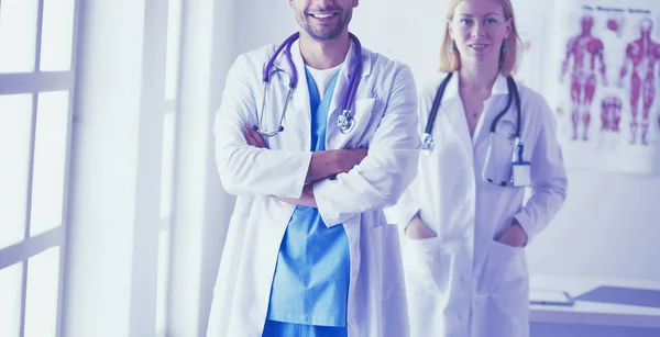 El guapo doctor está hablando con una joven doctora y tomando notas mientras está sentado en su consultorio.. — Foto de Stock