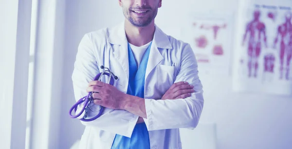 Retrato médico masculino joven y confiado de pie en el consultorio médico. — Foto de Stock