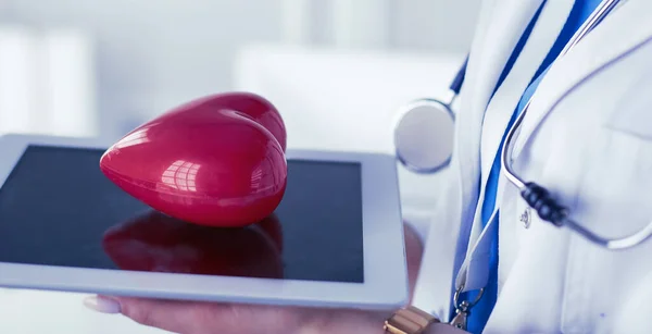 Doctora con estetoscopio sosteniendo el corazón, sobre fondo claro —  Fotos de Stock