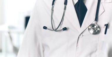 Genç ve kendinden emin erkek doktor portresi tıp ofisinde duruyor.