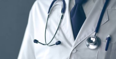 Genç ve kendinden emin erkek doktor portresi tıp ofisinde duruyor.