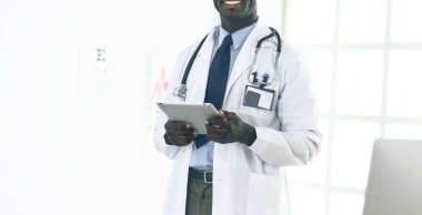 Tablet bilgisayarlı siyahi bir doktor hastanede bekliyor.