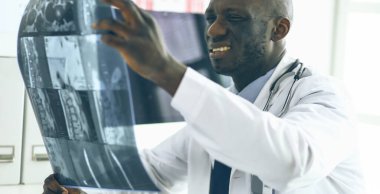 Genç Afrikalı doktor portresi hastaların röntgenlerini tutuyor.
