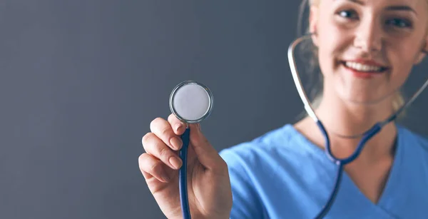 Femme médecin avec un stéthoscope à l'écoute, isolée sur fond gris — Photo