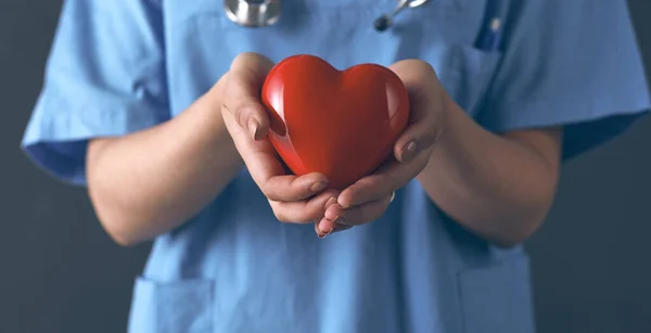 Doctor con estetoscopio sosteniendo el corazón, aislado sobre fondo gris — Foto de Stock