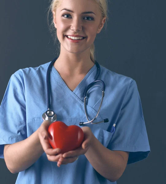 Доктор со стетоскопом держит сердце, изолированное на сером фоне — стоковое фото