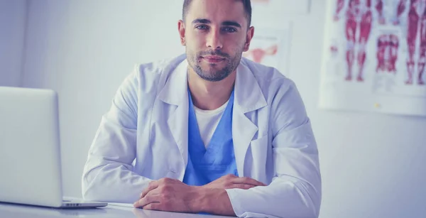 Retrato de un médico varón con portátil sentado en el escritorio en el consultorio médico — Foto de Stock