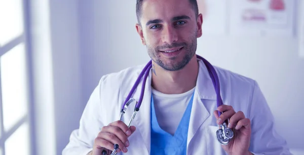 Молодий і впевнений чоловік доктор портрет стоячи в медичному кабінеті . — стокове фото