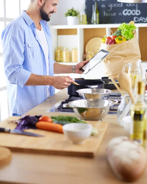 Mann folgt Rezept auf digitalem Tablet und kocht leckeres und gesundes Essen in der heimischen Küche — Stockfoto