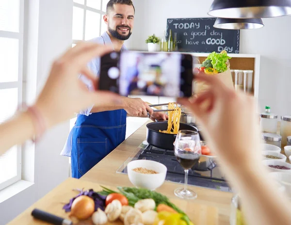 Uomo che prepara cibo delizioso e sano nella cucina di casa. Il suo video per il suo blog. — Foto Stock