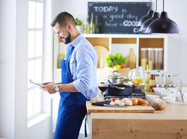 Man efter recept på digital tablett och matlagning välsmakande och hälsosam mat i köket hemma — Stockfoto