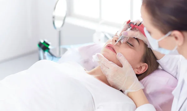 Mujer joven sometida a procedimiento de maquillaje permanente de cejas en salón de belleza —  Fotos de Stock